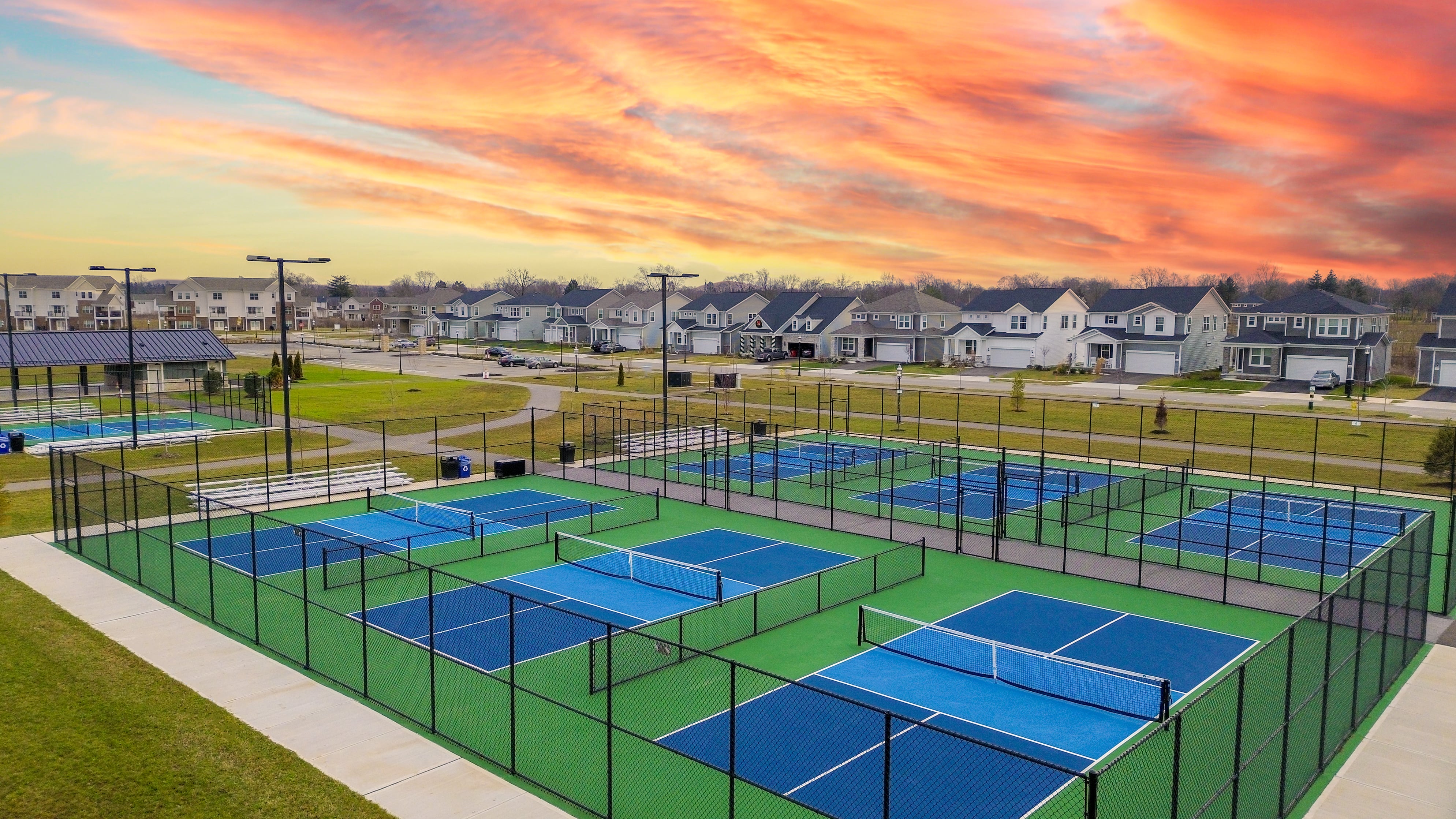 Pickleball courts at The Strand at Beulah Townhomes in Grove City, featuring multiple outdoor courts, walking paths, and a neighborhood setting at sunset.
