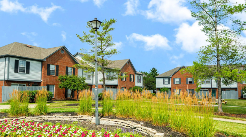 Exterior view of Copperleaf townhomes featuring landscaped grounds, green space, and spacious two-bedroom homes.