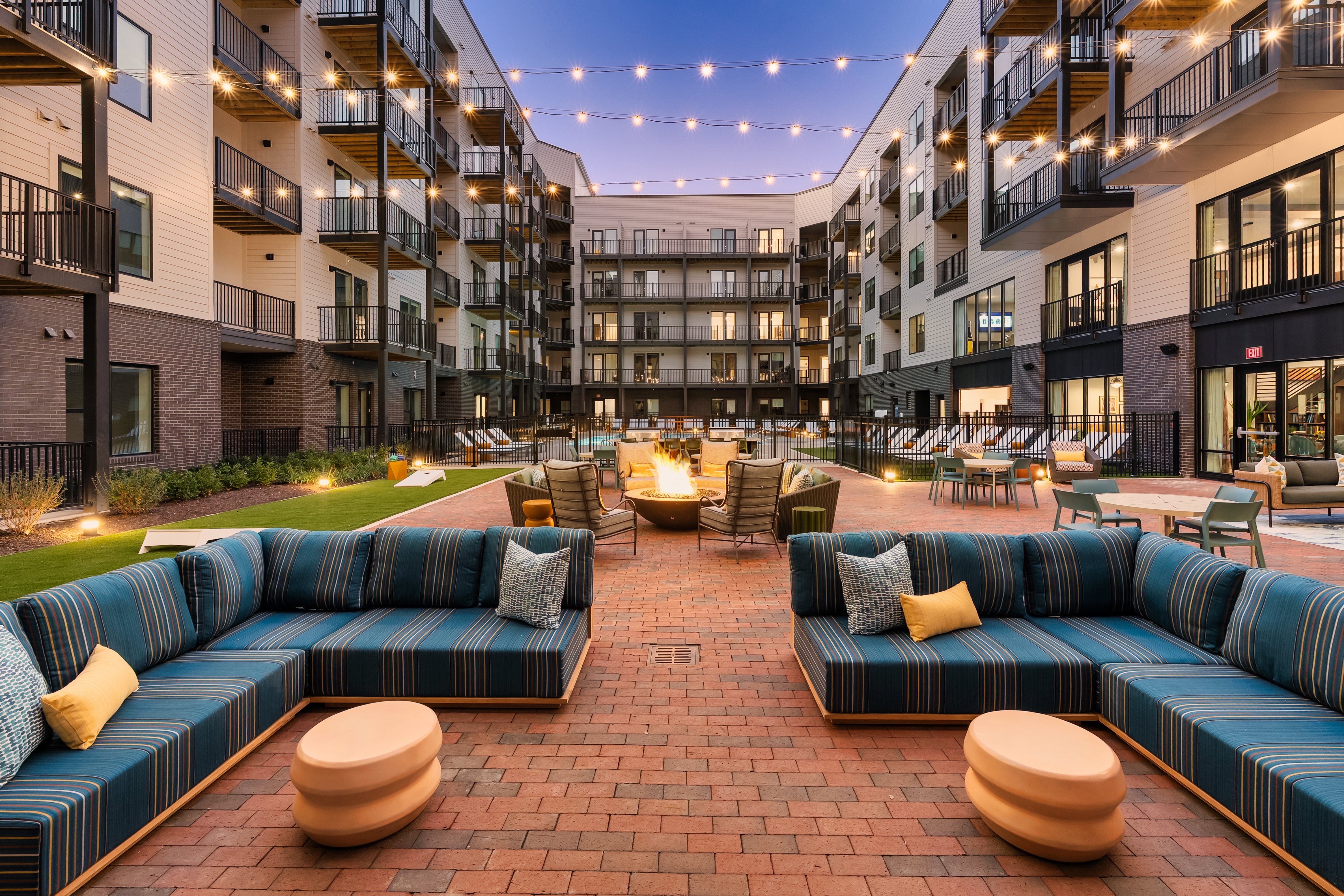 Resort style pool courtyard at Galaxy at Polaris apartments in Columbus, Ohio with fire pit seating, string lights, and outdoor lounge area.