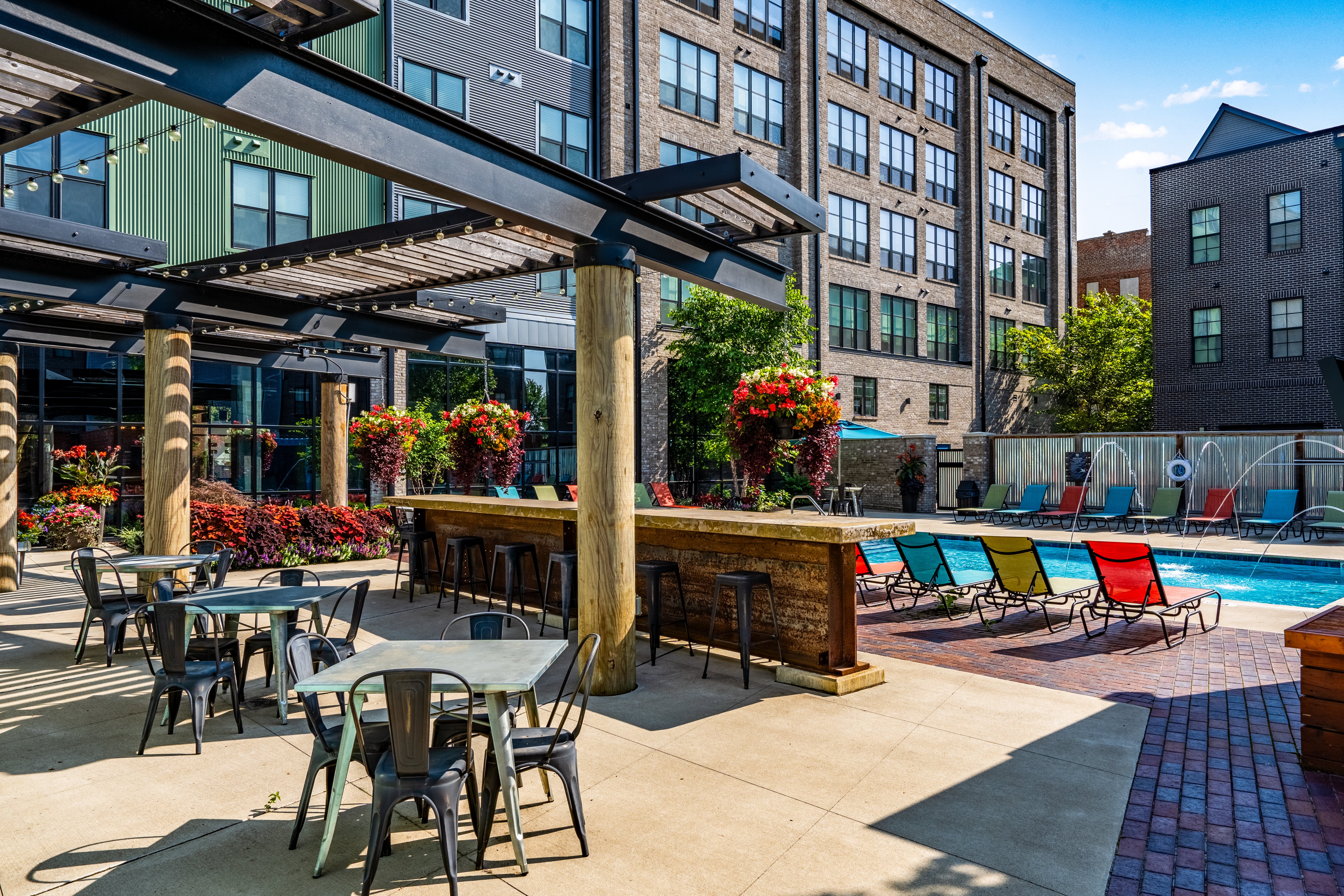 Resort style pool and outdoor lounge area at River and Rich apartments in Columbus, Ohio with seating, cabana, and colorful chairs.