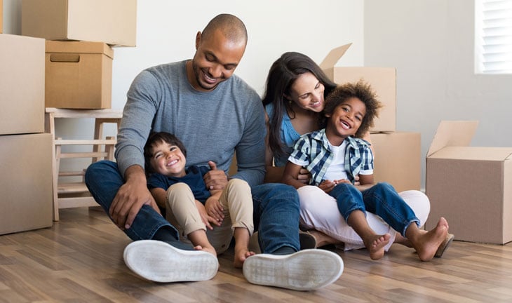 Happy family sitting on floor of first apartment on move-in day