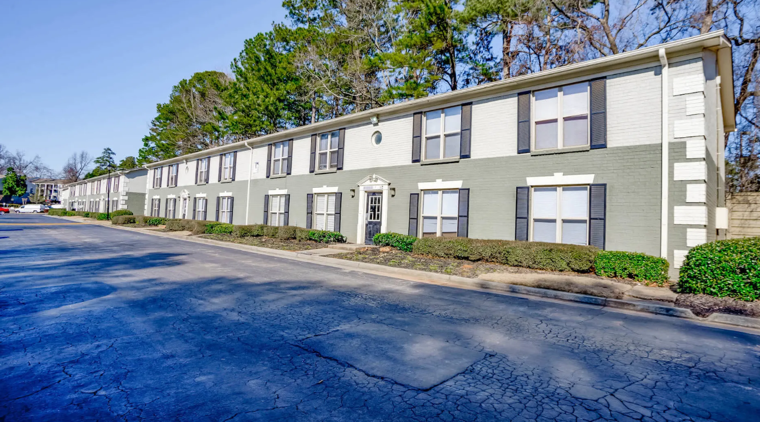 Two-story apartment exterior with black shutters and manicured landscaping at Elliot Norcross