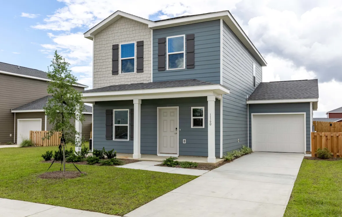 Two-story rental home at Outpost Orchard in Foley featuring a private garage, covered front porch, and landscaped yard.