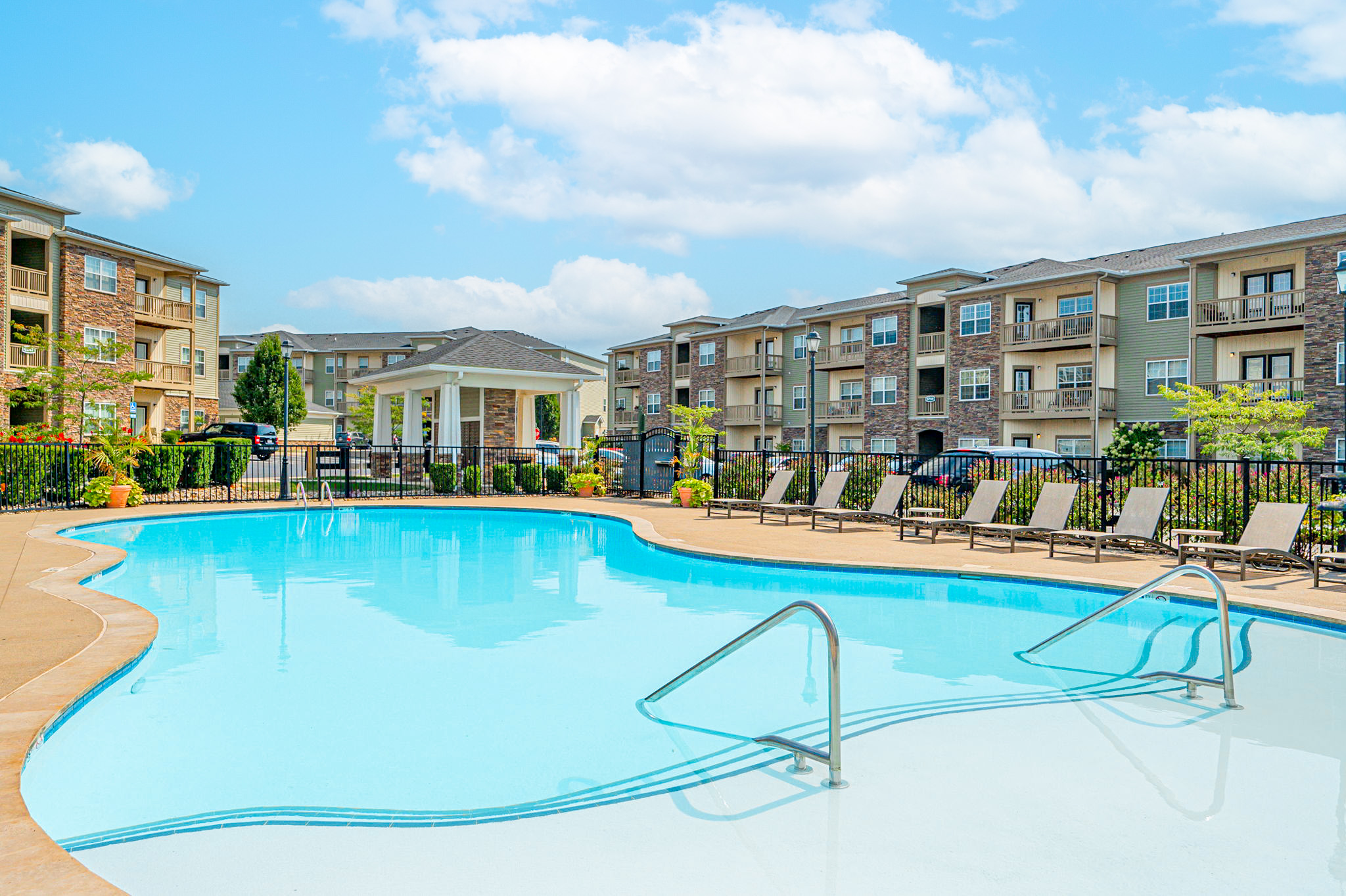 Family-friendly resort-style swimming pool with lounge chairs and landscaped surroundings at Albany Corners Apartments in New Albany, Ohio.