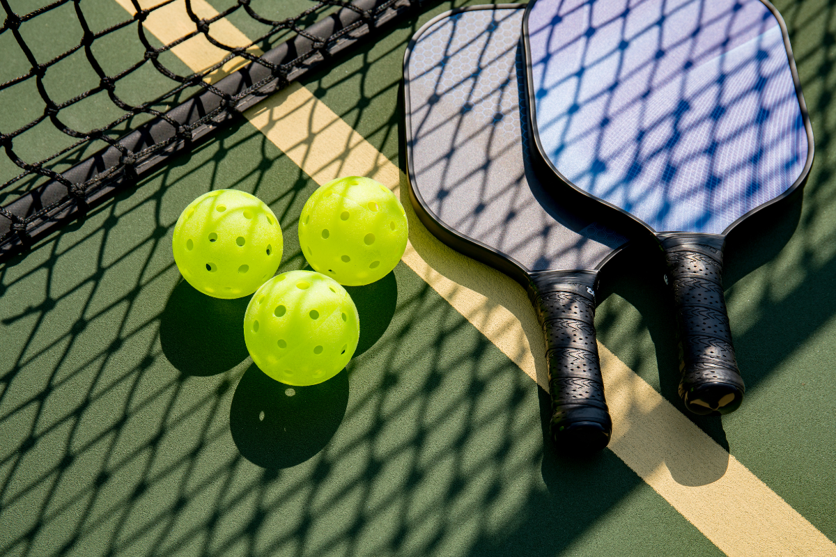 Pickleball paddles and ball on a court highlighting the growing popularity of apartments with pickleball courts in Columbus, Ohio.