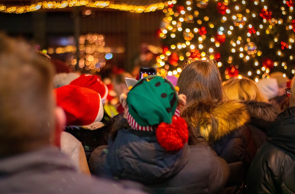 New Rochelle Christmas tree lighting crowd with people wearing Santa hats and festive green beanie.