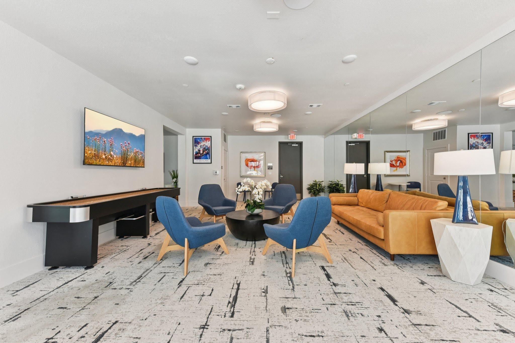 Resident lounge at SOFI at 6311 with shuffleboard table, blue armchairs, and an orange sofa