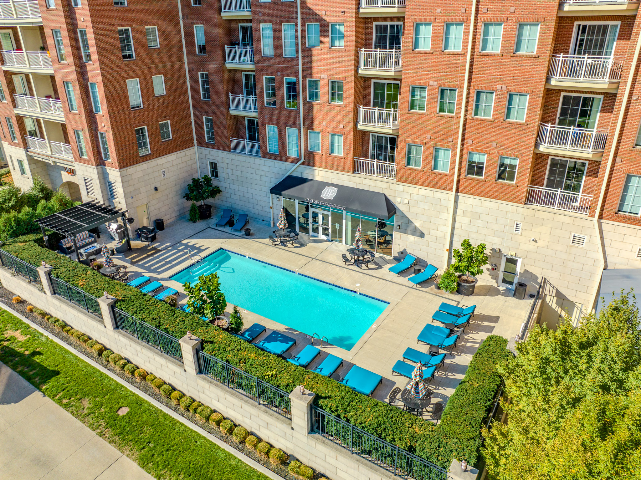 Rooftop resort-style swimming pool at Highpoint on Columbus Commons with lounge chairs and panoramic views of the Downtown Columbus skyline at sunset.
