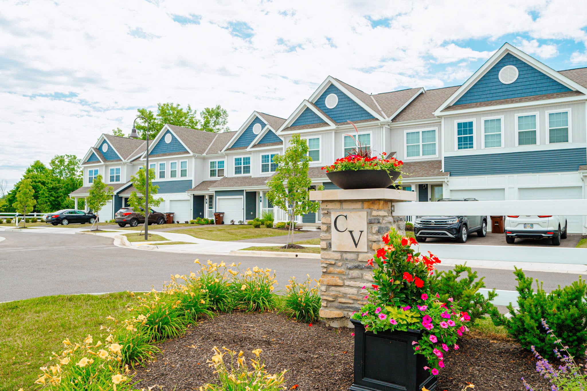 Cheswick Village townhomes in Powell, Ohio featuring attached garages, private driveways, and landscaped community entrance.