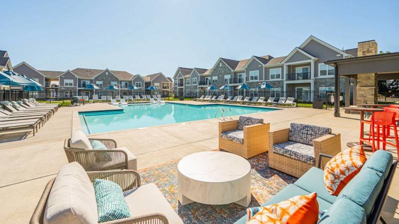 Resort-style outdoor pool area at The Retreat at Mount Vernon Apartments featuring lounge seating, umbrellas, and modern poolside furniture.