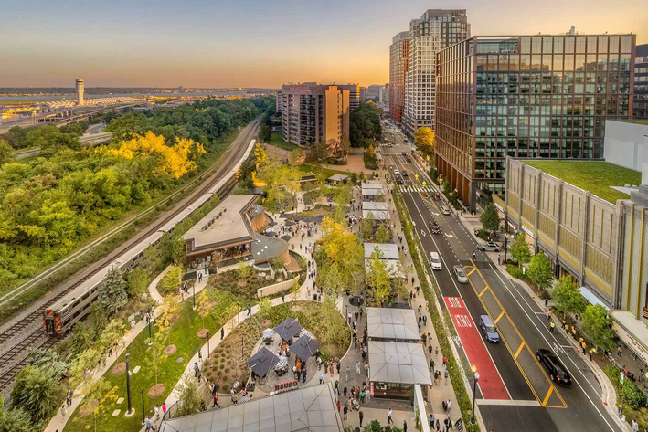 Crystal Drive in National Landing, Arlington, Virginia at dusk, with the rail line and Reagan National Airport in the distance