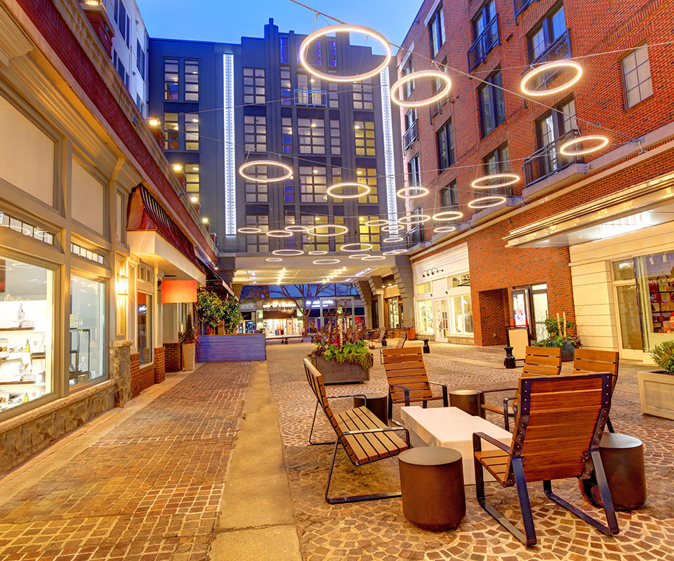 Pedestrian-friendly Bin downtown Bethesda, Maryland at night, with string lights, outdoor dining, and walkable mixed-use buildings