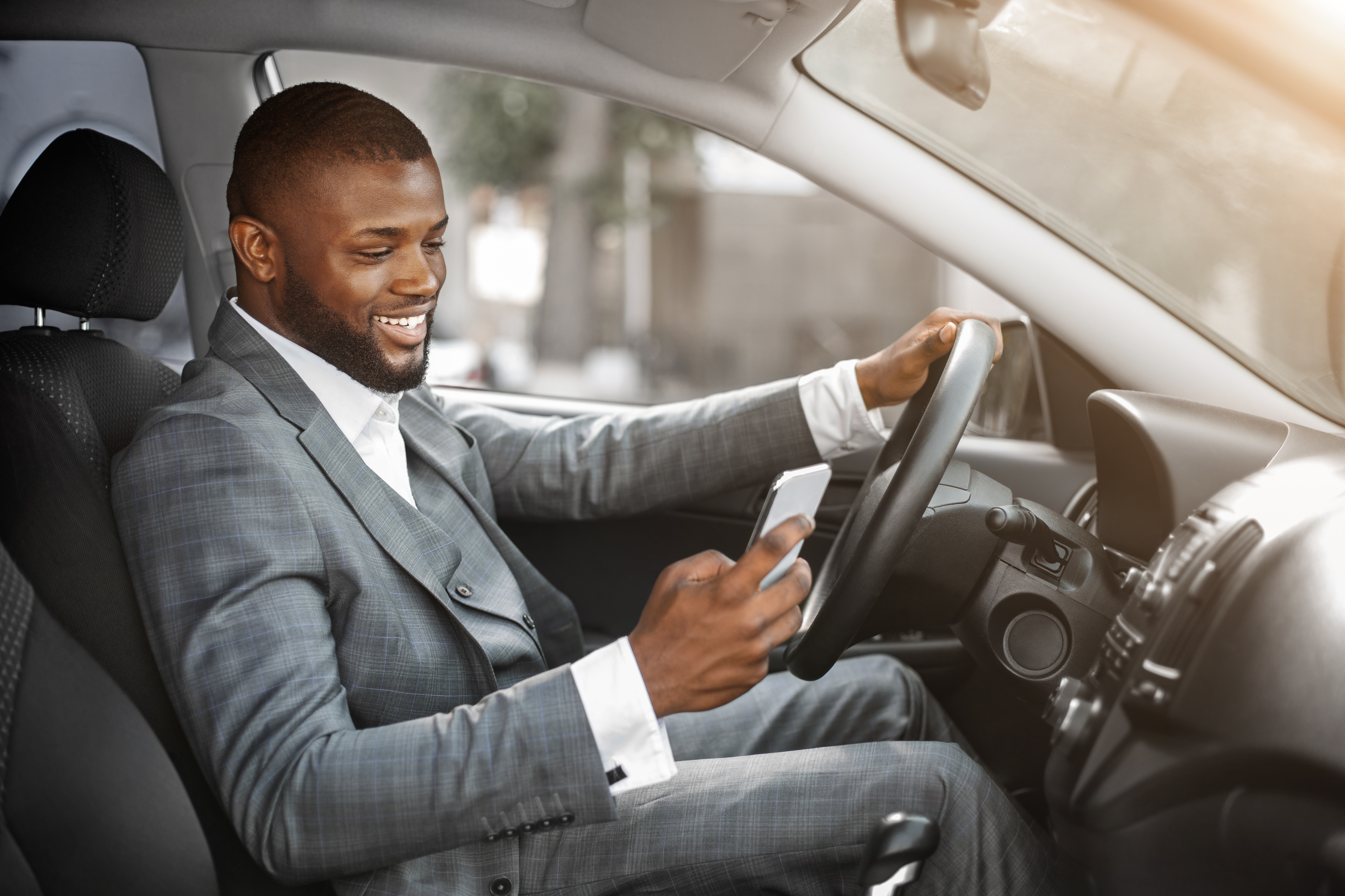 well dressed man in suit driving and checking cellphone