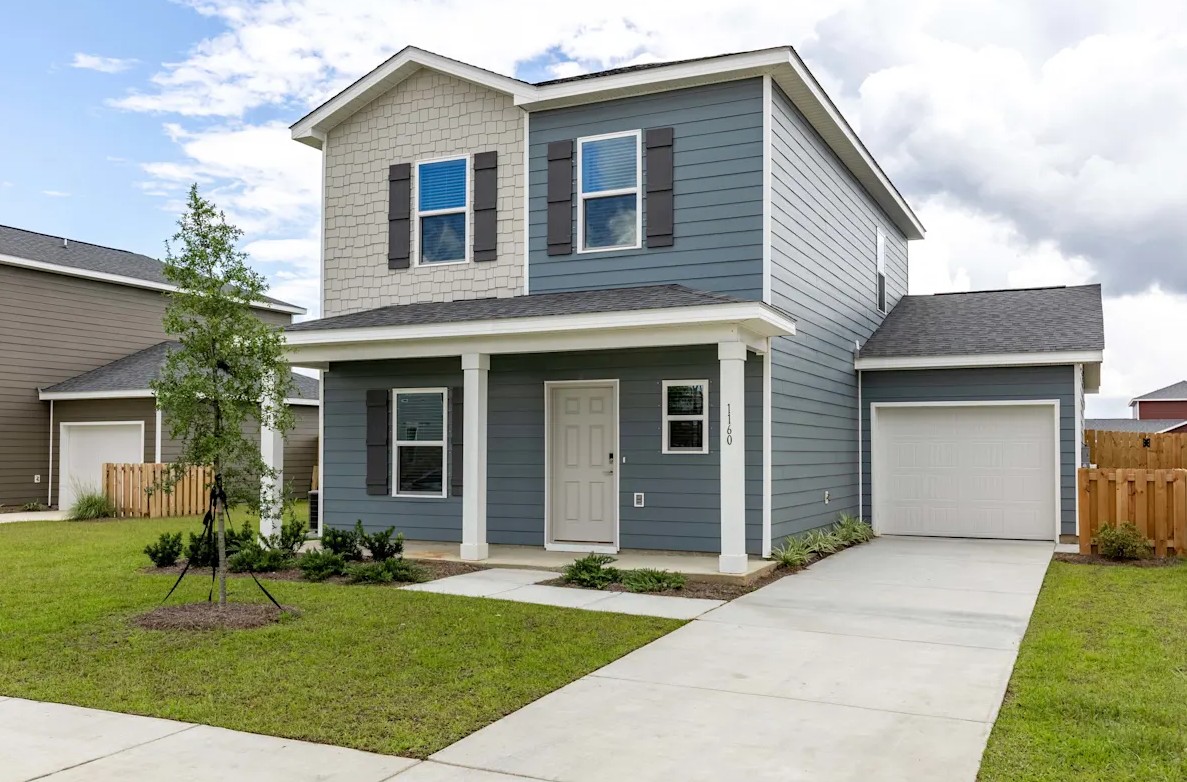 Exterior of a modern two-story rental home with blue siding, tan shingles, and a front porch at Outpost Orchard in Foley, AL.