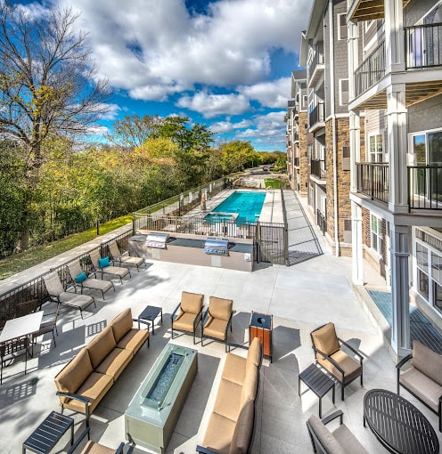 overlook of deck and patio with chairs and outdoor furniture and barbeque grills and in-ground swimming pool at The Oaks of Shorewood in Shorewood, WI.
