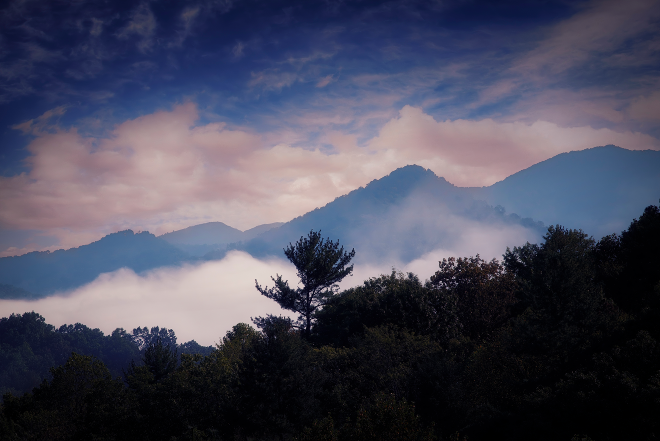 Fog rolling through the Blue Ridge Mountains in North Carolina beneath a colorful sunrise sky.