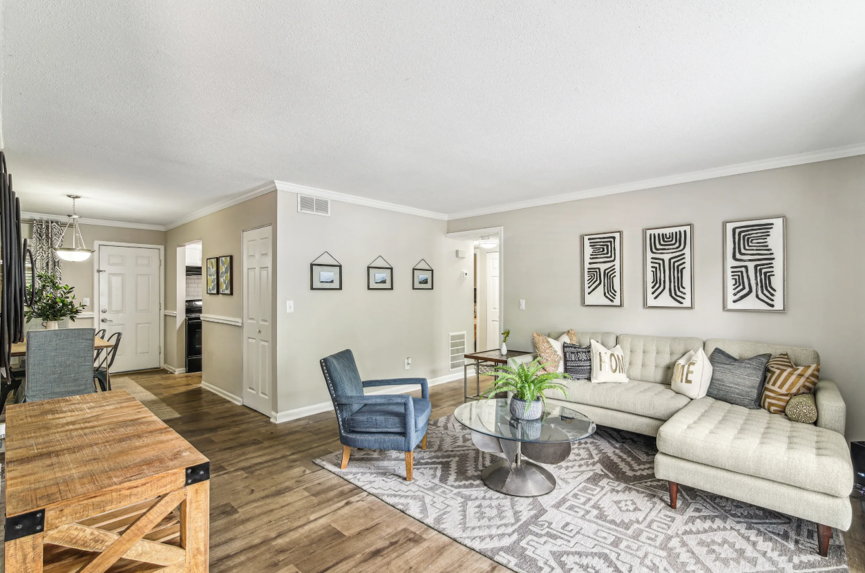 Open-concept apartment living room with hardwood floors, gray sectional, and crown molding