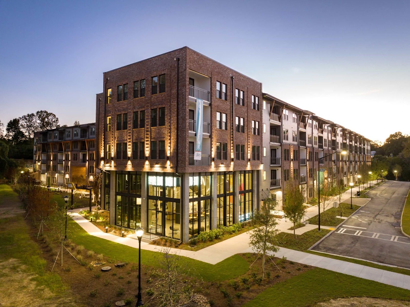 A twilight drone photo of The Argos Apartments at Grant Park, showing the modern brick and glass building exterior and streetscape.