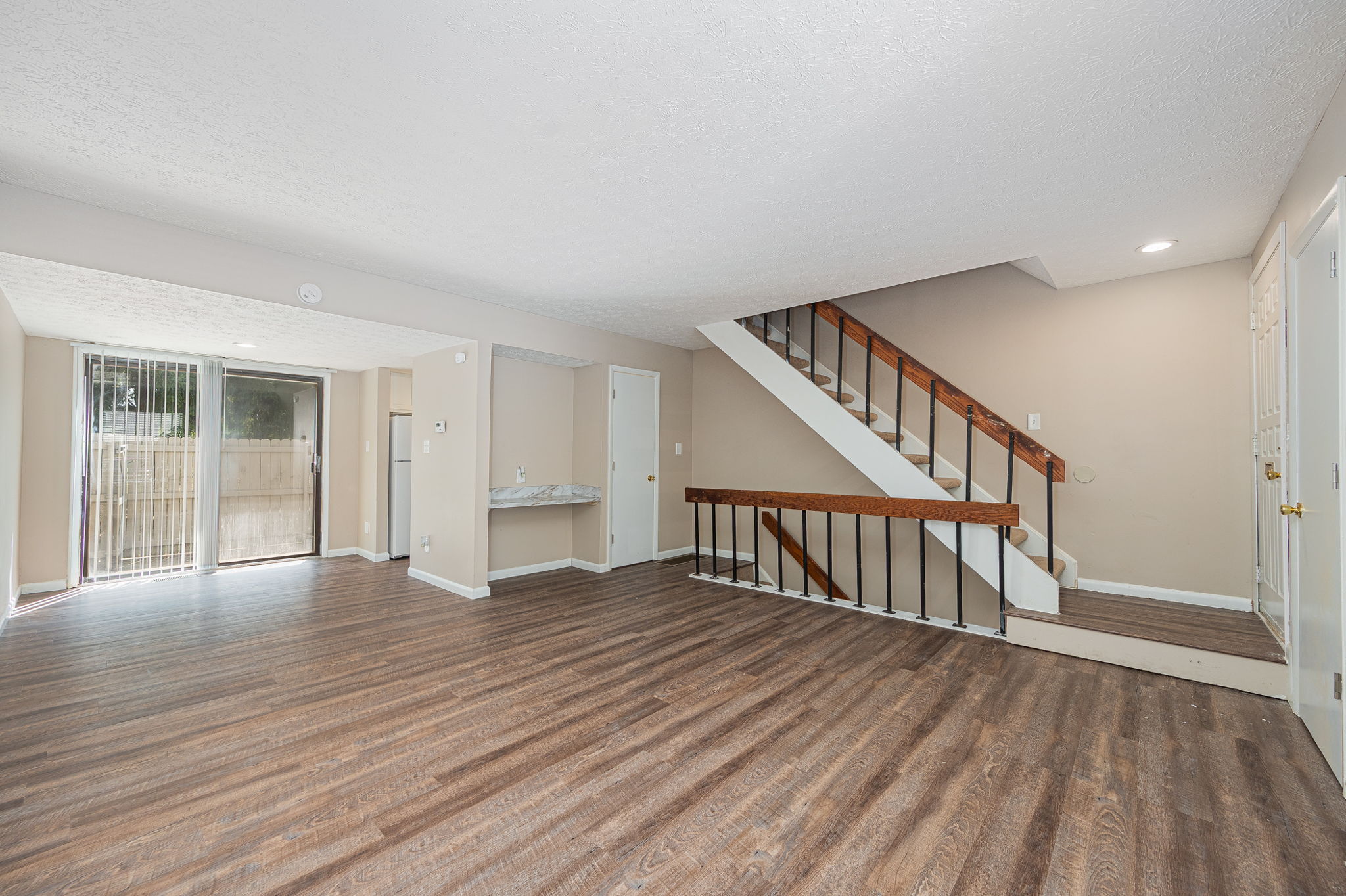 Spacious townhome interior at Stonehedge featuring an open living area, luxury vinyl plank flooring, and a private patio.