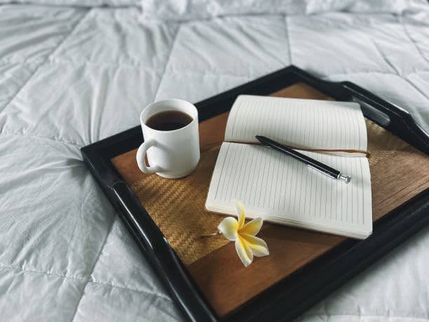 A peaceful morning scene with coffee, an open journal, and soft bedding at The Kirkwood Apartments at Edgewood.
