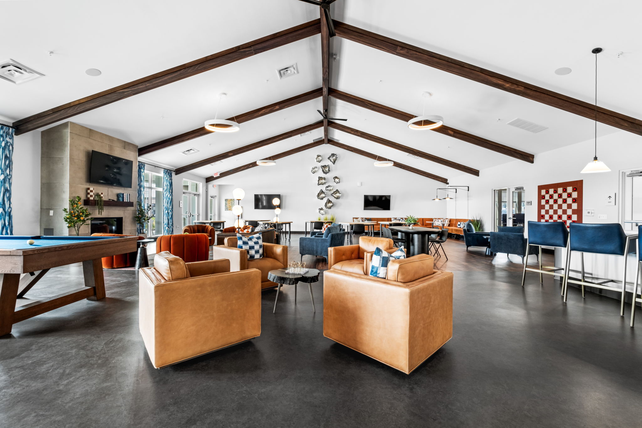 Modern resident clubhouse at Zelle at Polaris apartments featuring leather seating, pool table, lounge areas, and vaulted wood-beam ceilings.