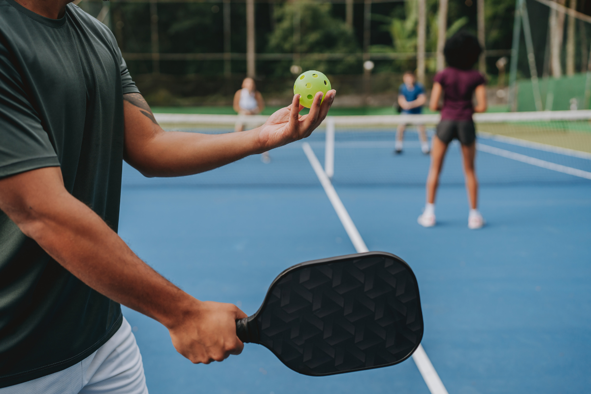 Player holding a pickleball and paddle on a court before serving, highlighting Oakwood apartments with pickleball courts in Columbus, Ohio.