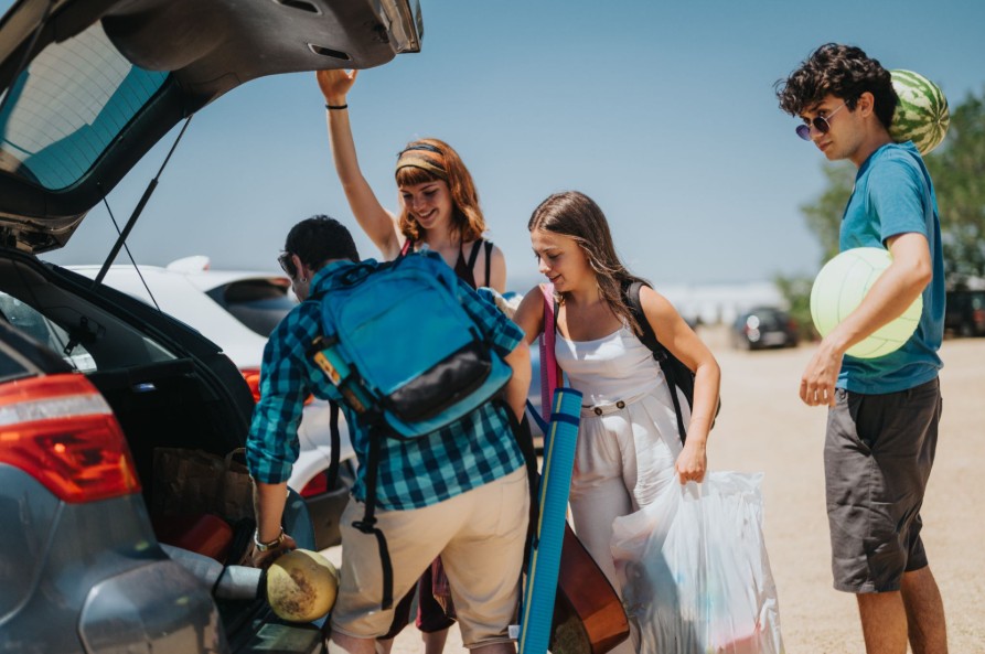 Friends unloading backpacks and beach gear from car trunk in Fairfield