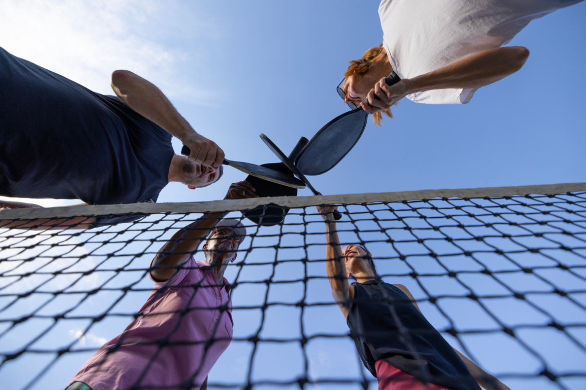 Group of friends playing pickleball on a court, showing the social appeal driving demand for apartments with pickleball courts in Columbus, Ohio.