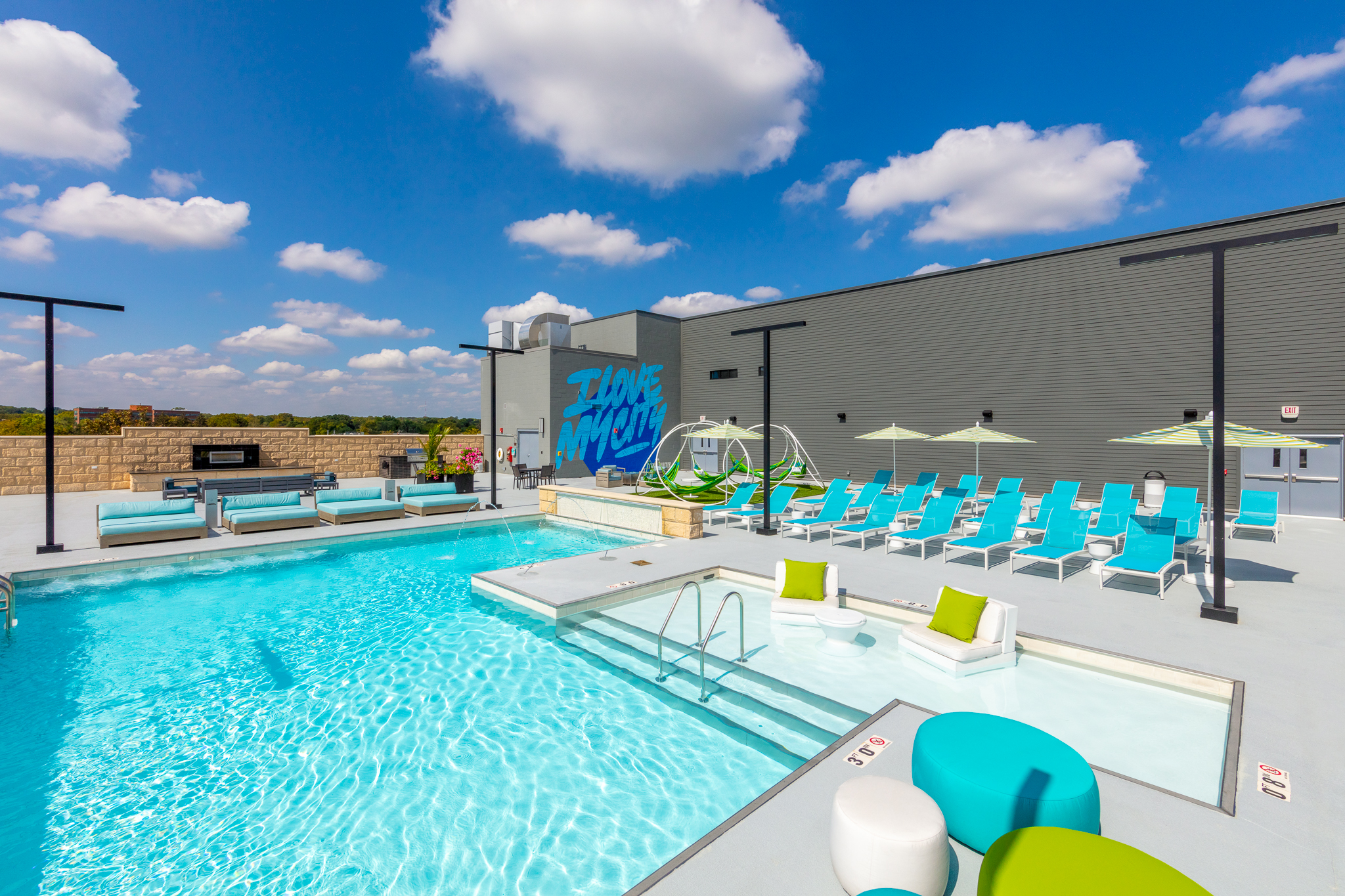 Rooftop pool deck at The City Apartments in downtown Columbus, featuring lounge chairs, hammock swings, and a modern fire pit.