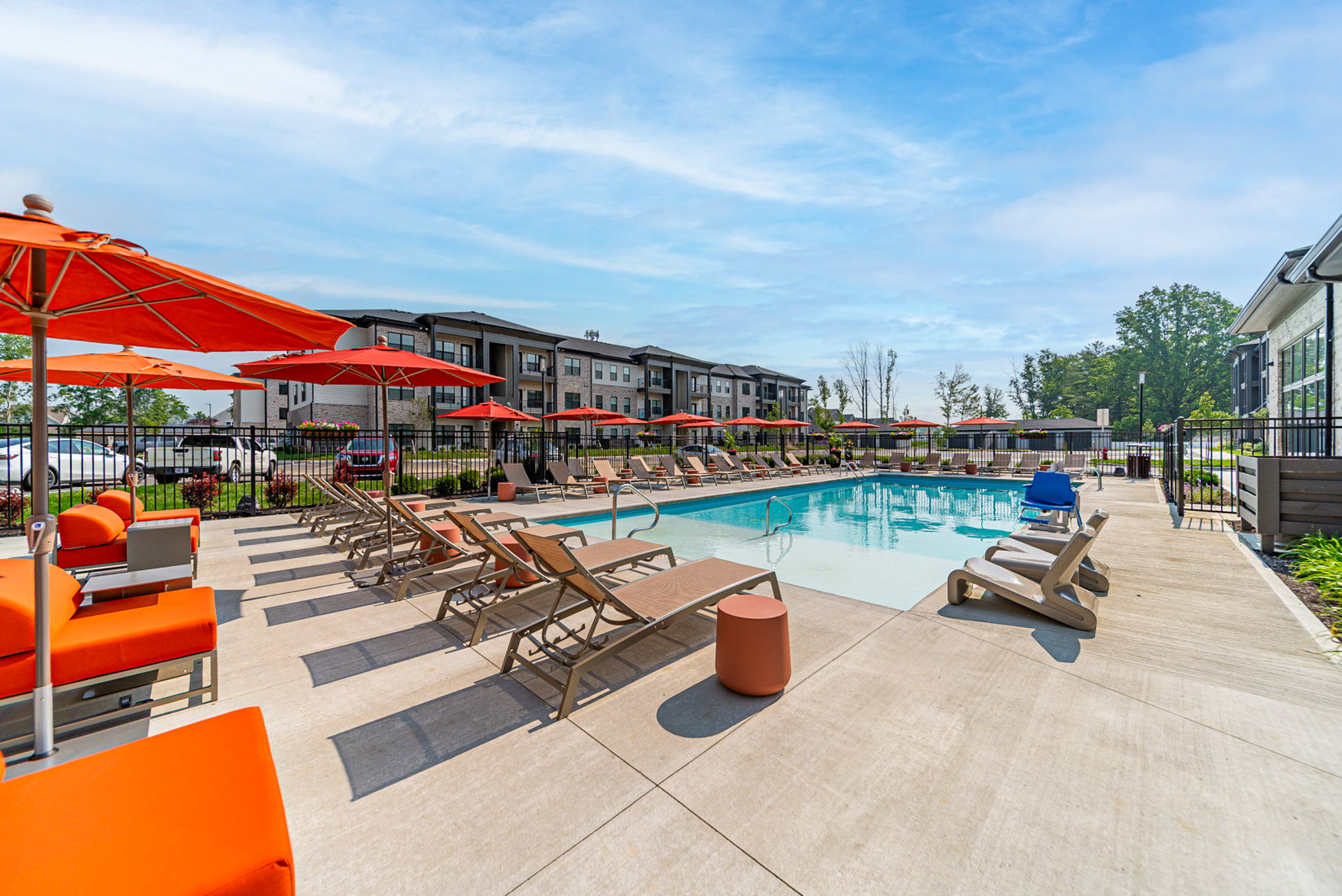Resort-style swimming pool with orange lounge chairs and umbrellas at Oxford Park Apartments in Westerville, Ohio managed by Oakwood.