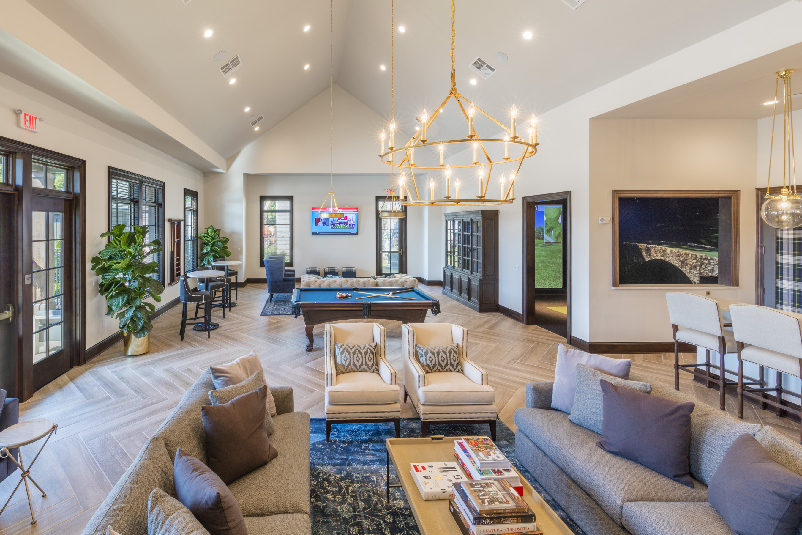Spacious clubhouse lounge at The Charles at Riggins Run in Hilliard, Ohio featuring modern seating, a pool table, large chandelier, and multiple work and relaxation areas.