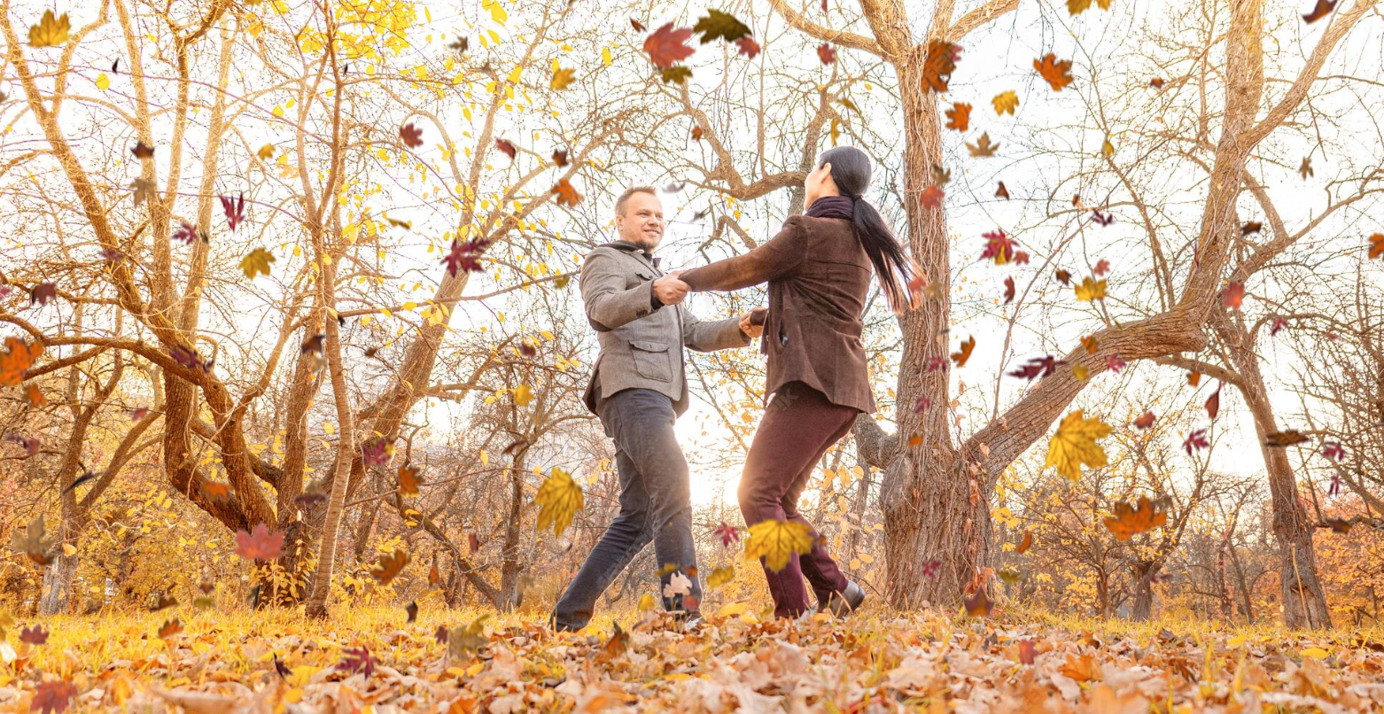 Happy couple enjoying a fall day in the outdoors at Wesley St. Claire Apartments in Lawrenceville, surrounded by colorful autumn leaves.
