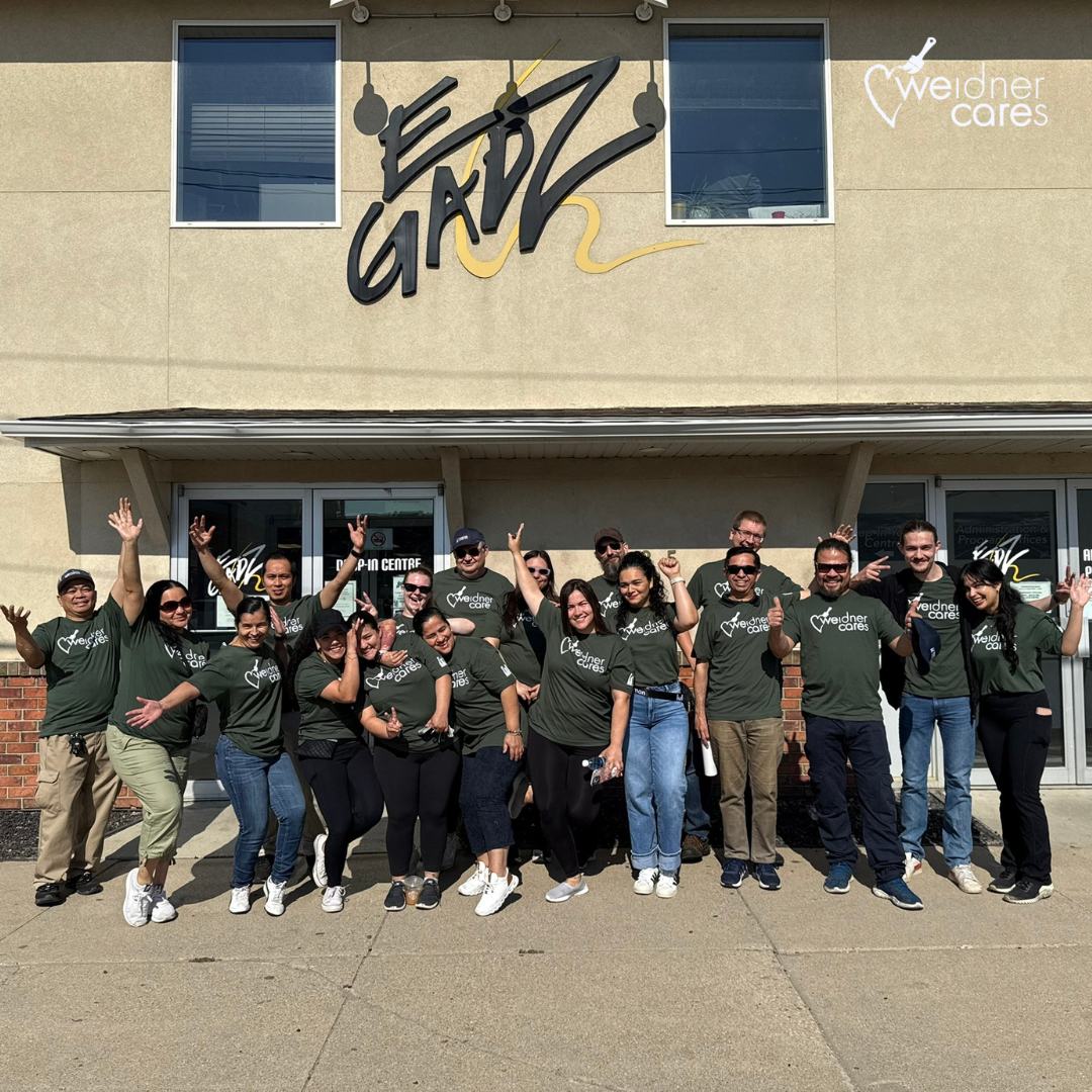 Image of Weidner associates in Saskatoon in front of the EGADZ building, posing with their green Weidner Cares t-shirts.