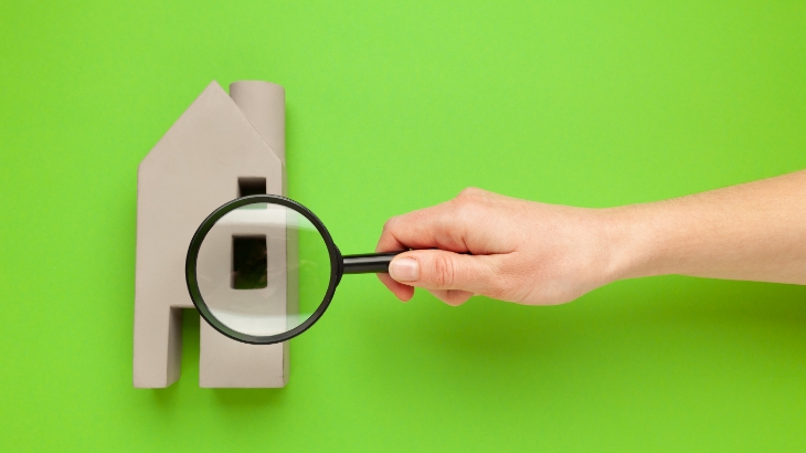 a cardboard apartment model is evaluated through a magnifying glass