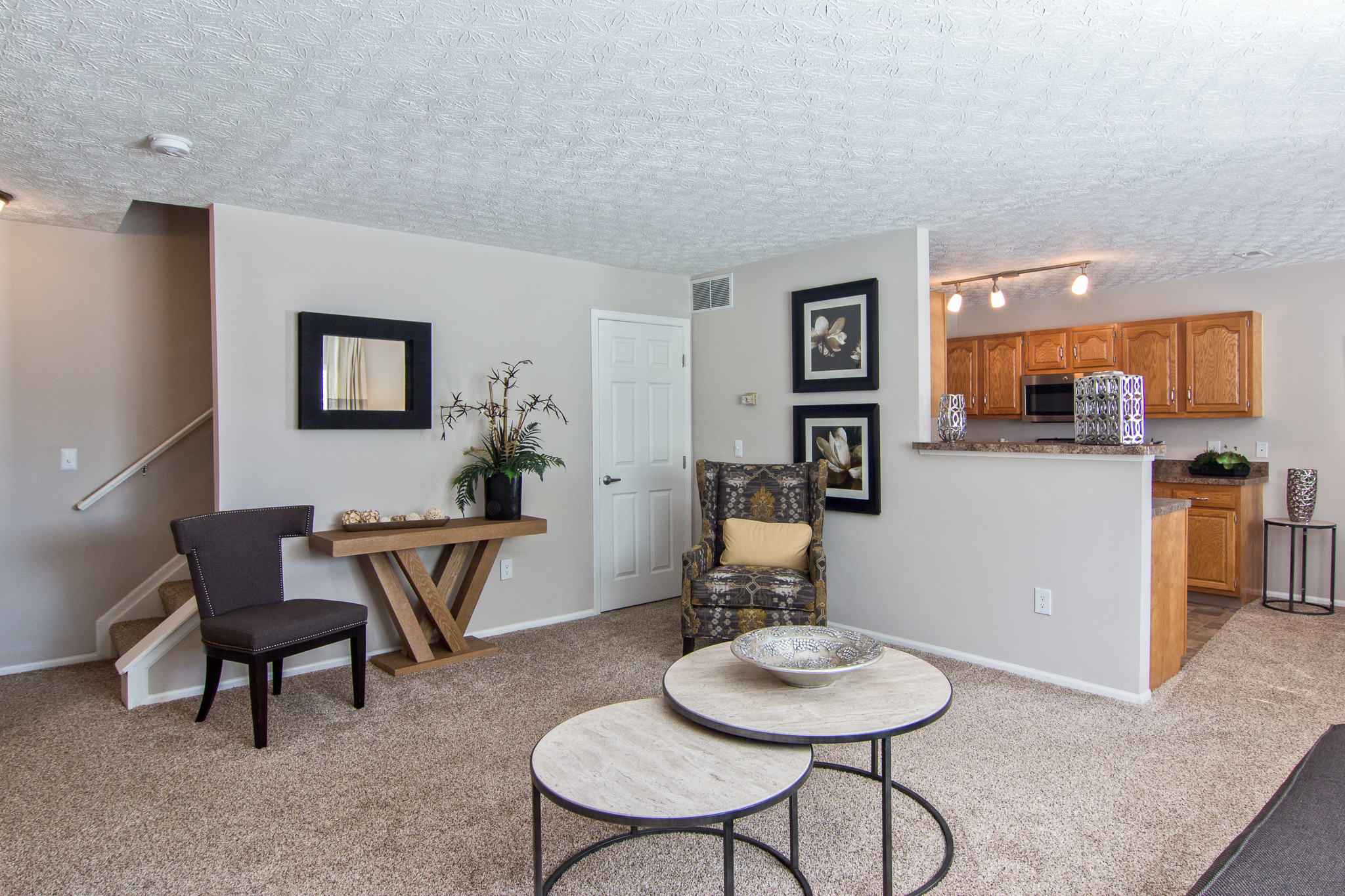 Spacious open-concept living room and kitchen at Albany Woods apartments in New Albany, Ohio, featuring a breakfast bar, modern finishes, and abundant natural light.