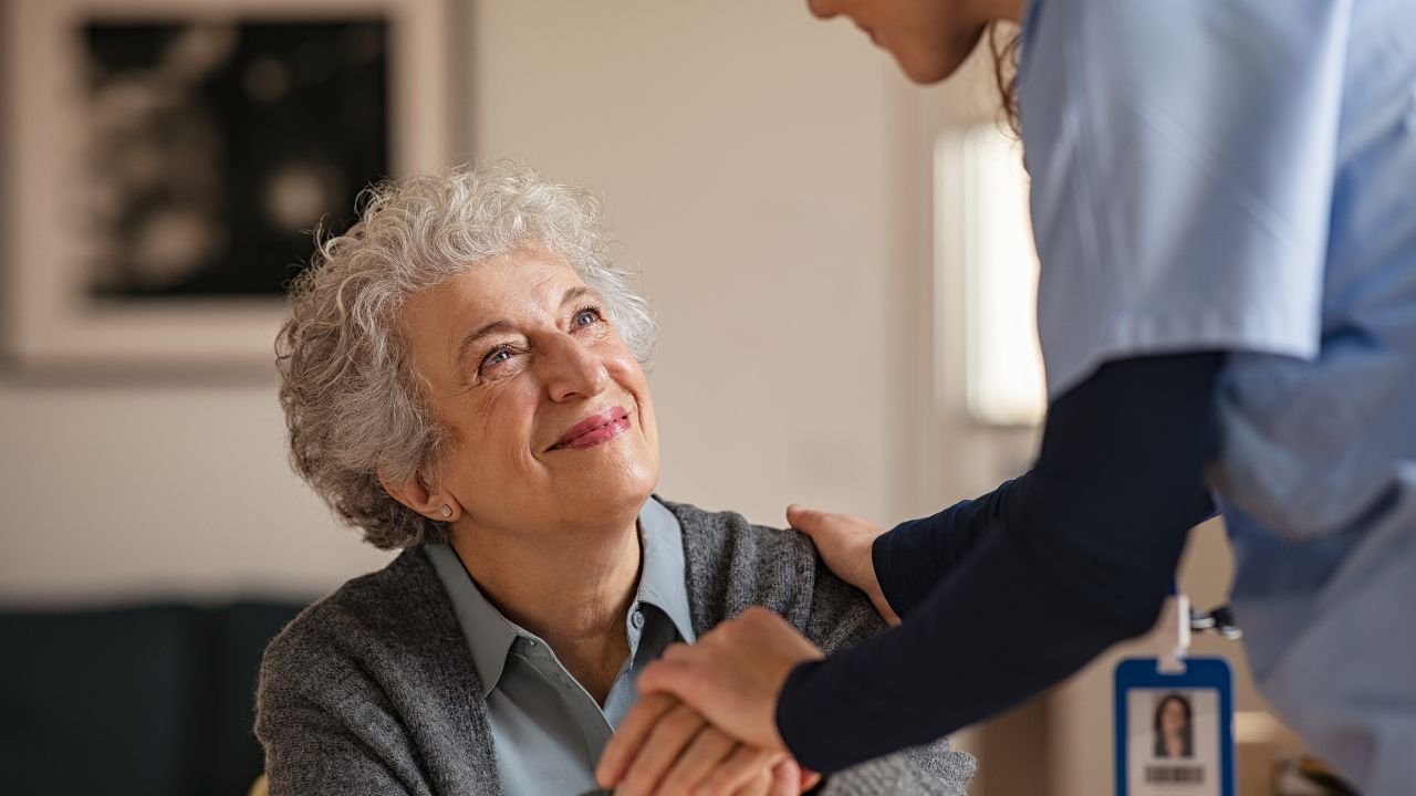 a happy senior smiling and looking up at nurse assisting her
