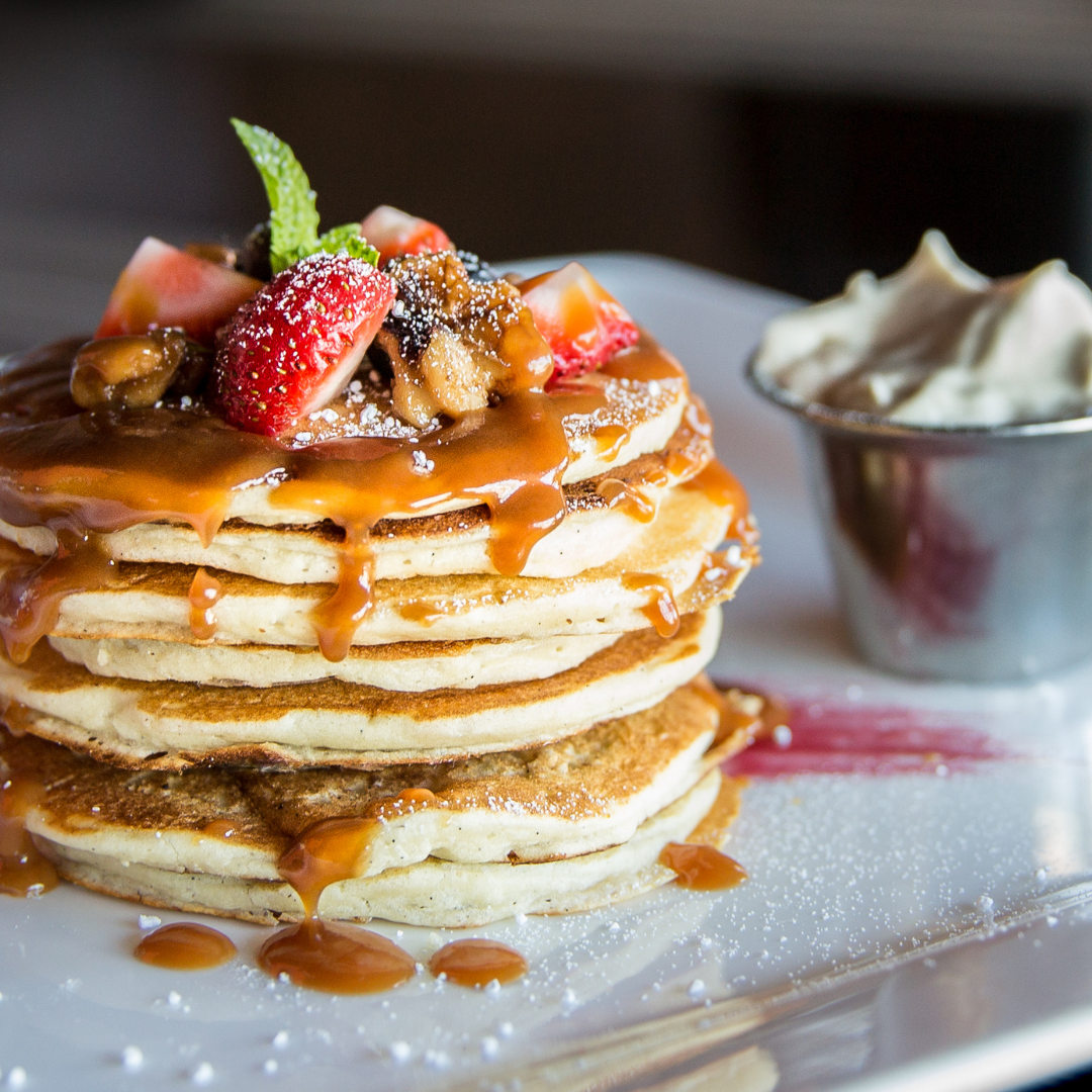Beautifully plated pancakes with syrup, powdered sugar, and fresh berries on top