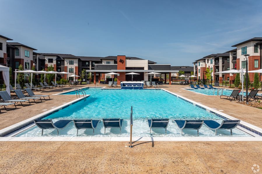 swimming pool with chairs and umbrellas at 49 West Apartment Homes . Rogers, AR