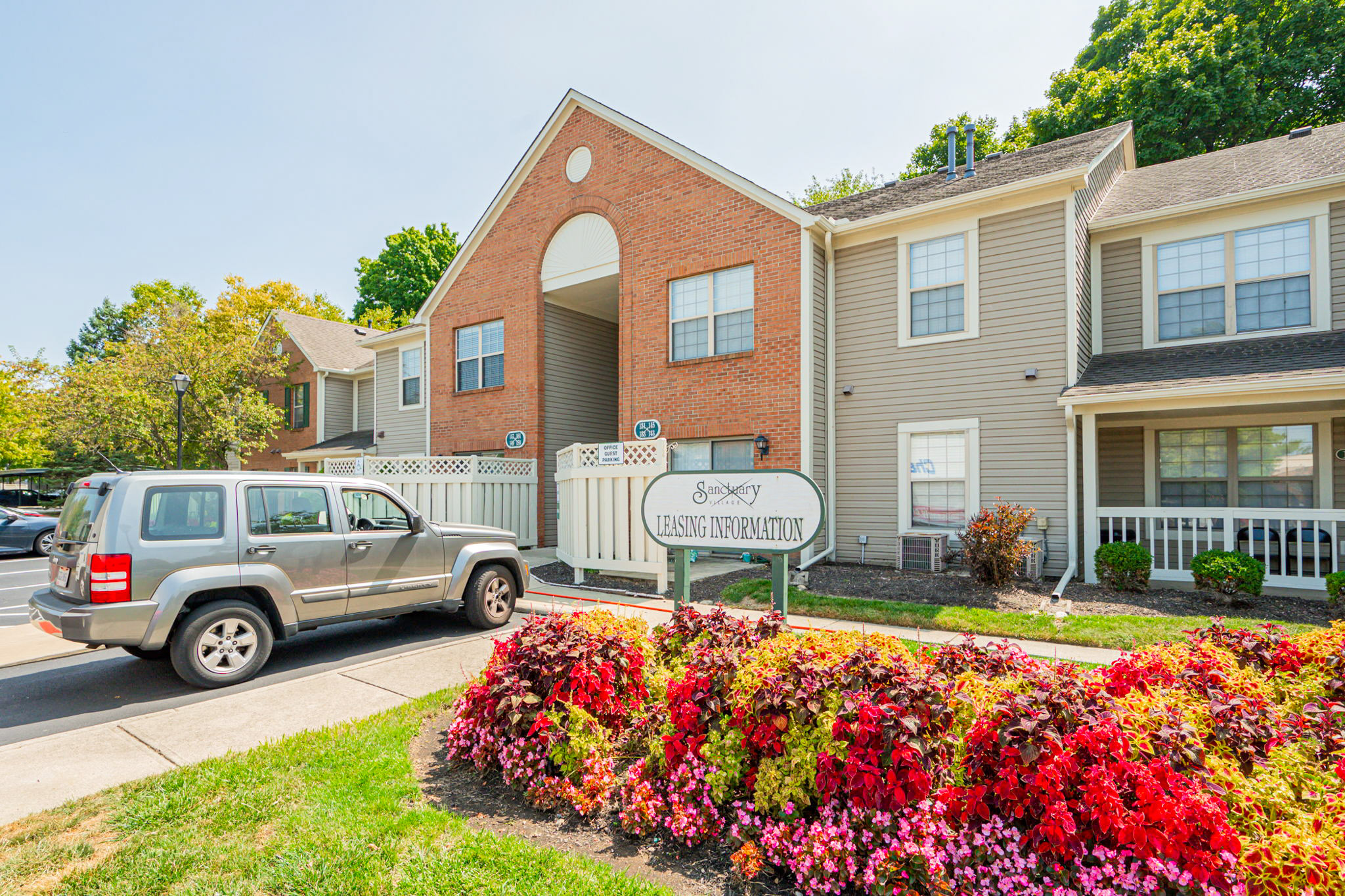 Exterior view of Sanctuary Village apartments featuring beautifully landscaped grounds, private entrances, and a welcoming residential setting.