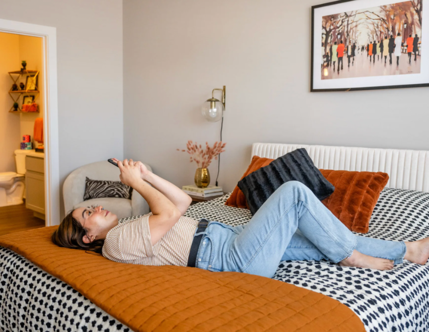 Resident relaxing in a cozy bedroom at Residences at Topiary Park, showcasing comfortable apartment living in Downtown Columbus.