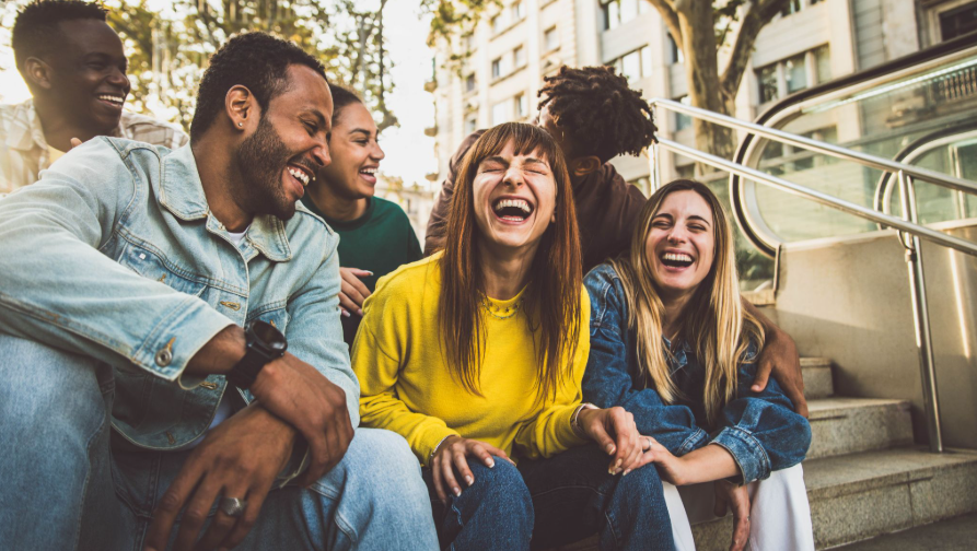 Diverse young adults laughing together on outdoor steps in New Rochelle