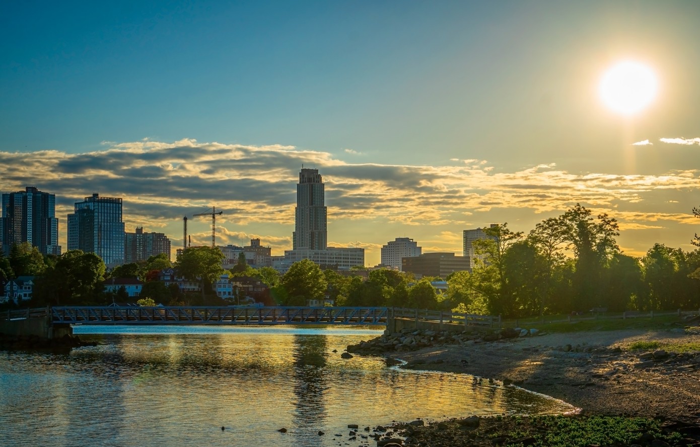 Scenic golden hour view of Five Islands Park bridge and downtown New Rochelle skyline across the water.