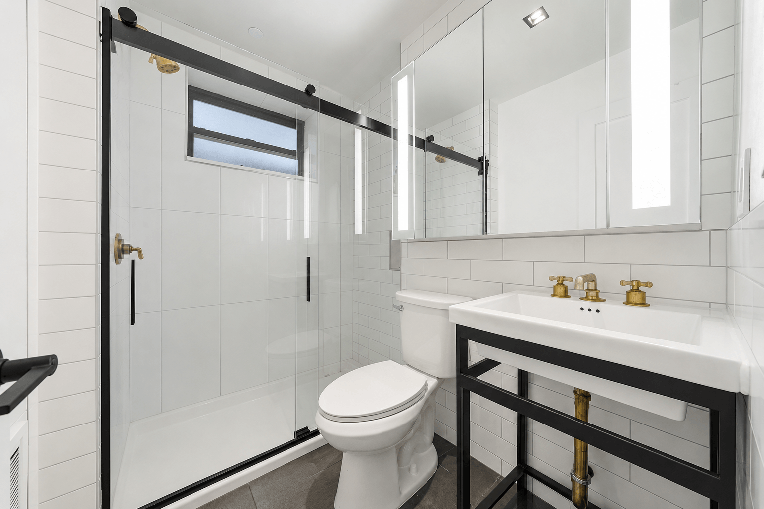 A white toilet sits in a bathroom with a black and white tile wall.