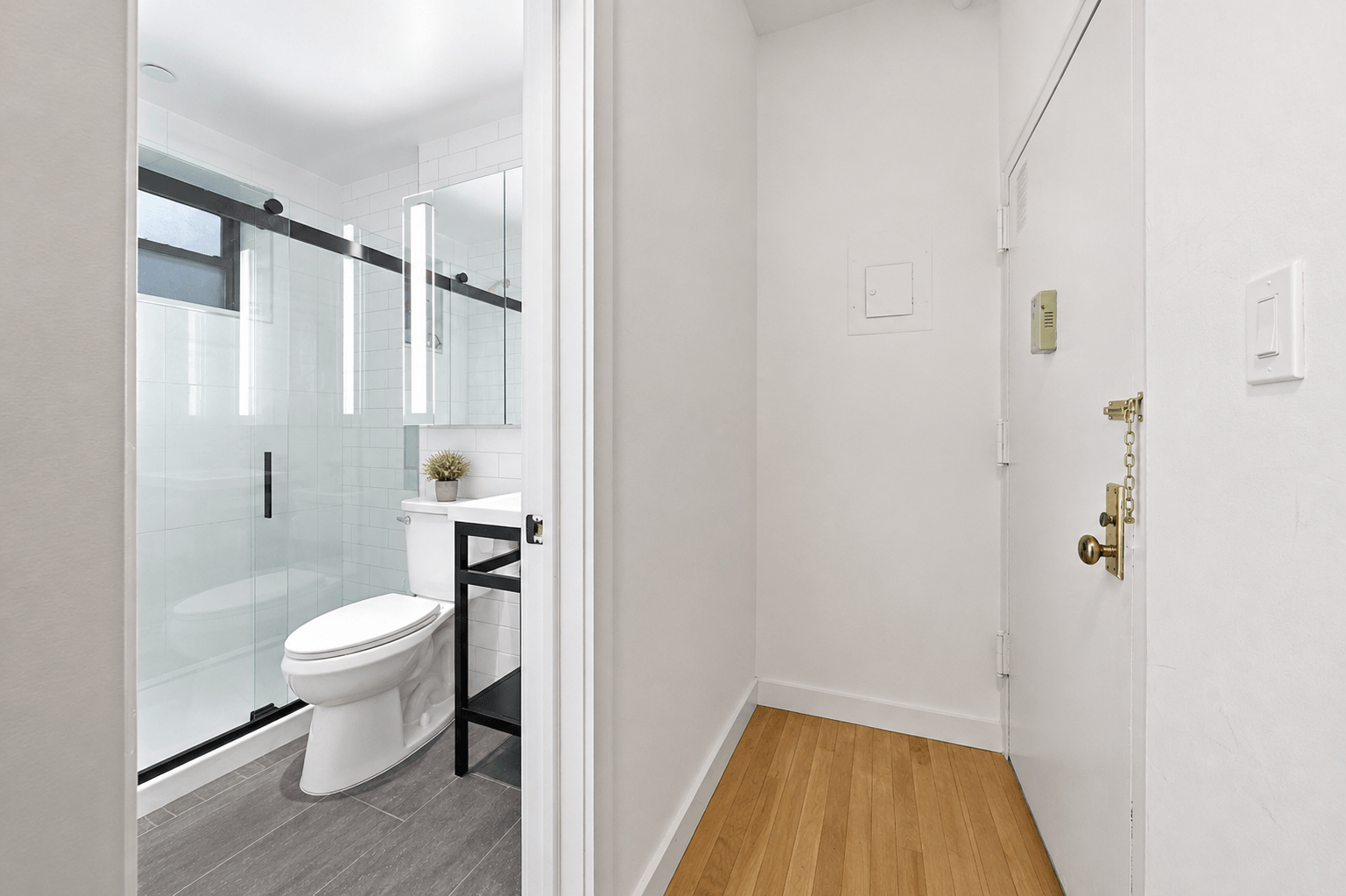 A white toilet is in a small bathroom with a glass door.