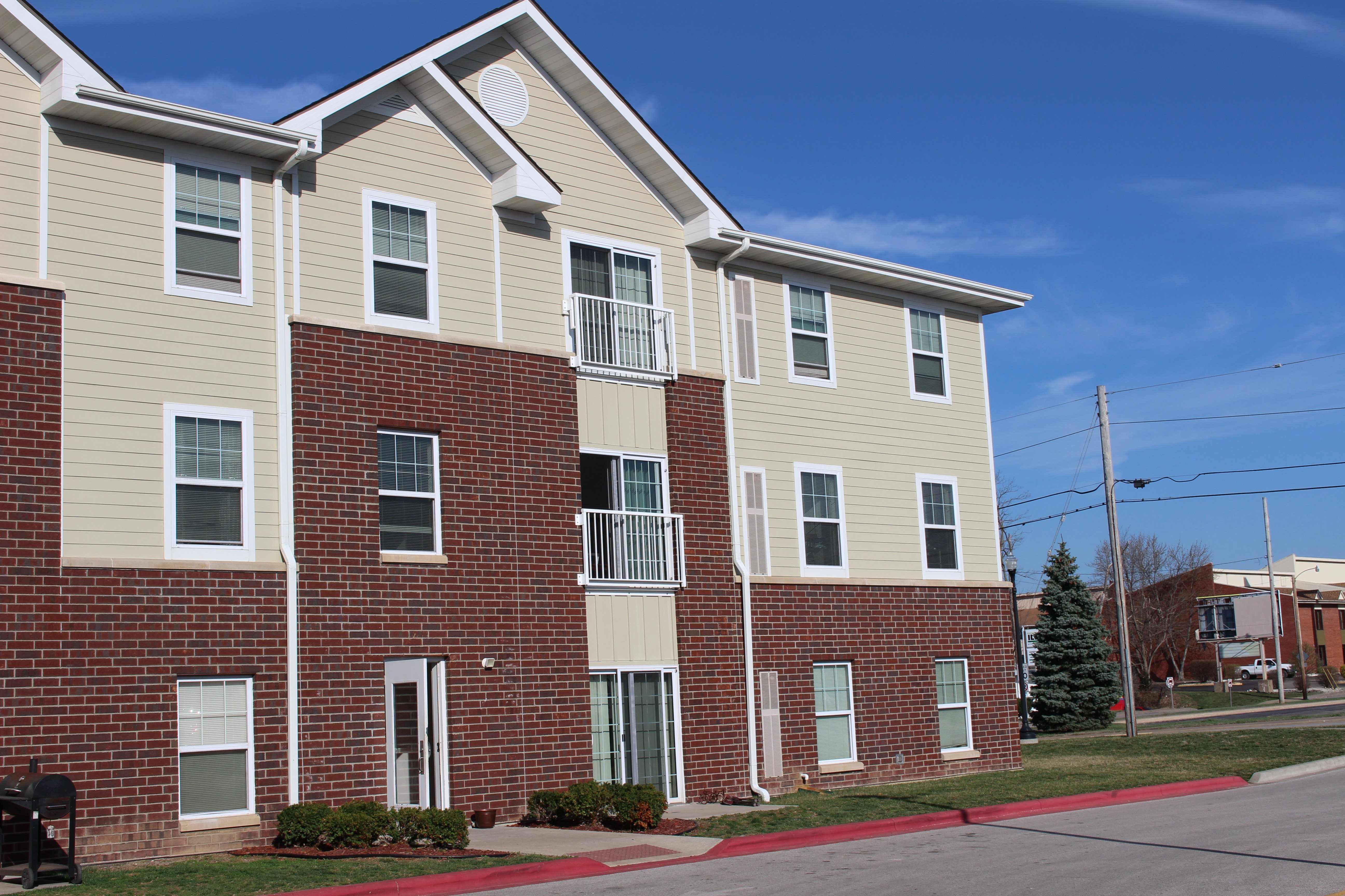 Apartment building with red brick and beige siding.