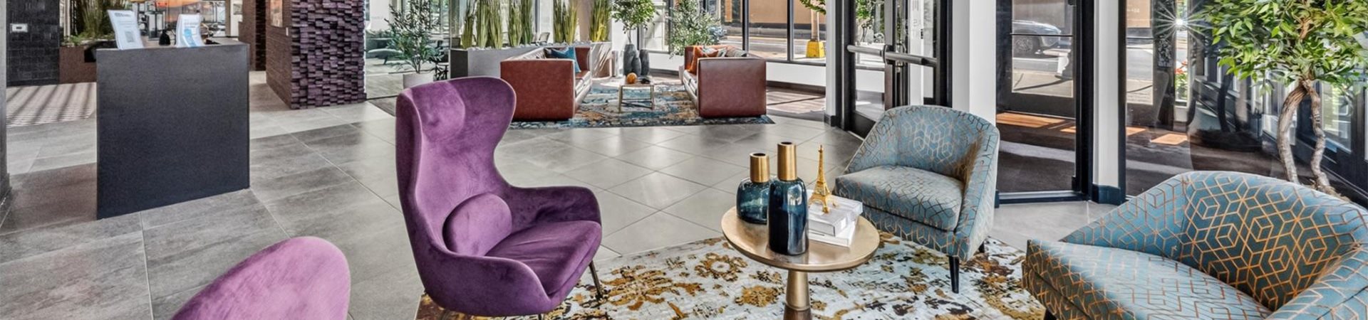 A purple chair sits in a room with a blue couch and a patterned rug.