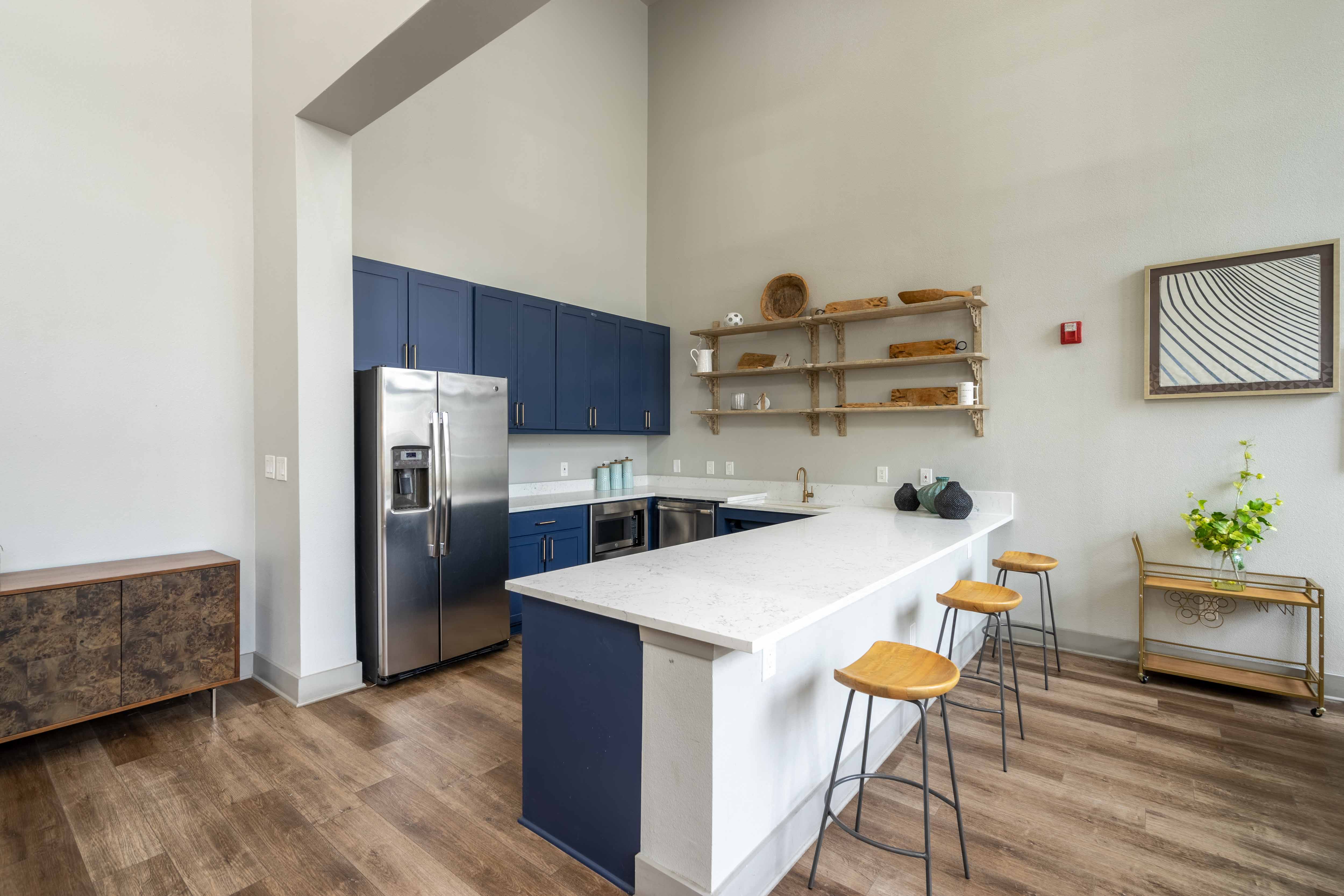 a kitchen with a large island with a white countertop and blue cabinets