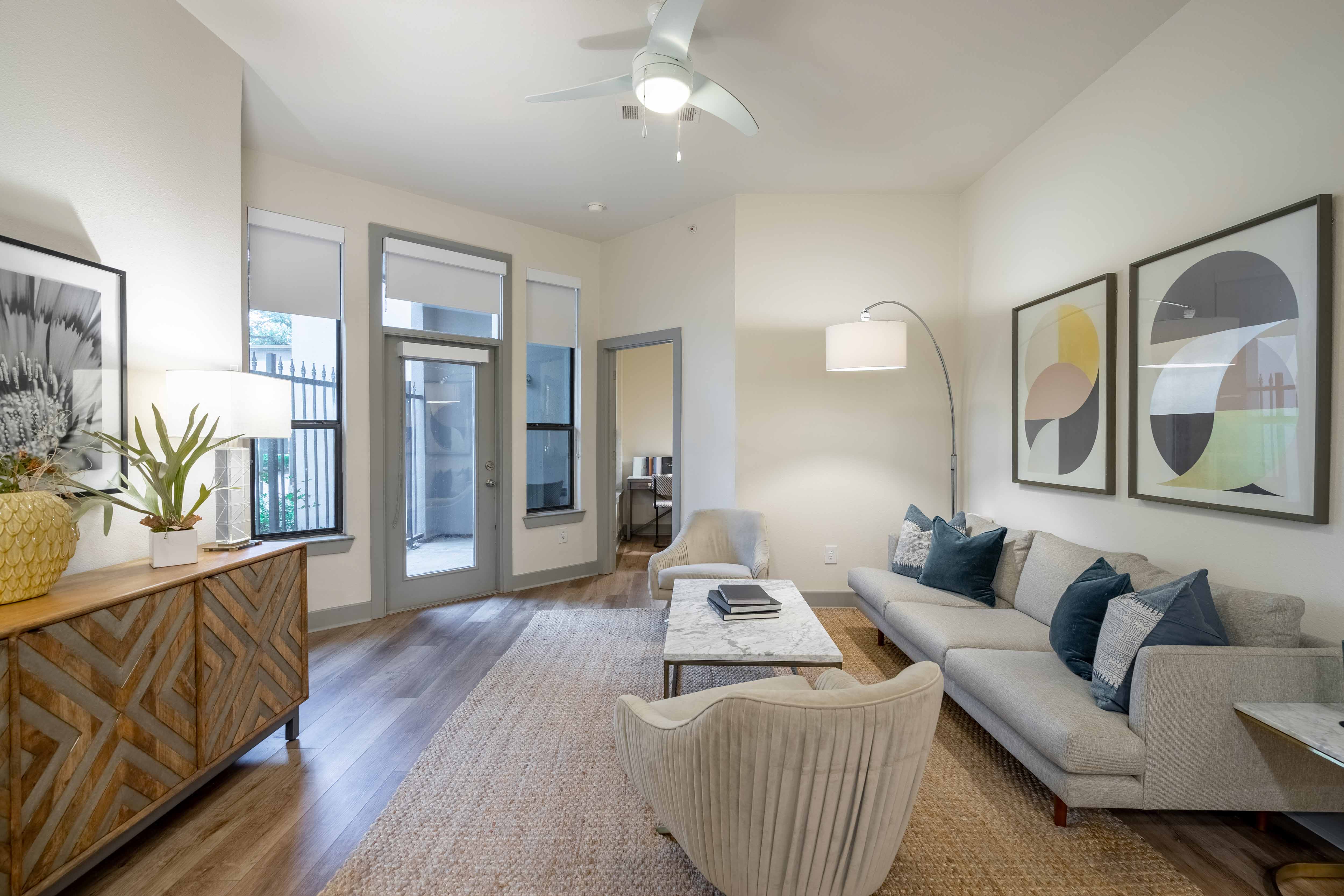 a living room with white walls and a ceiling fan