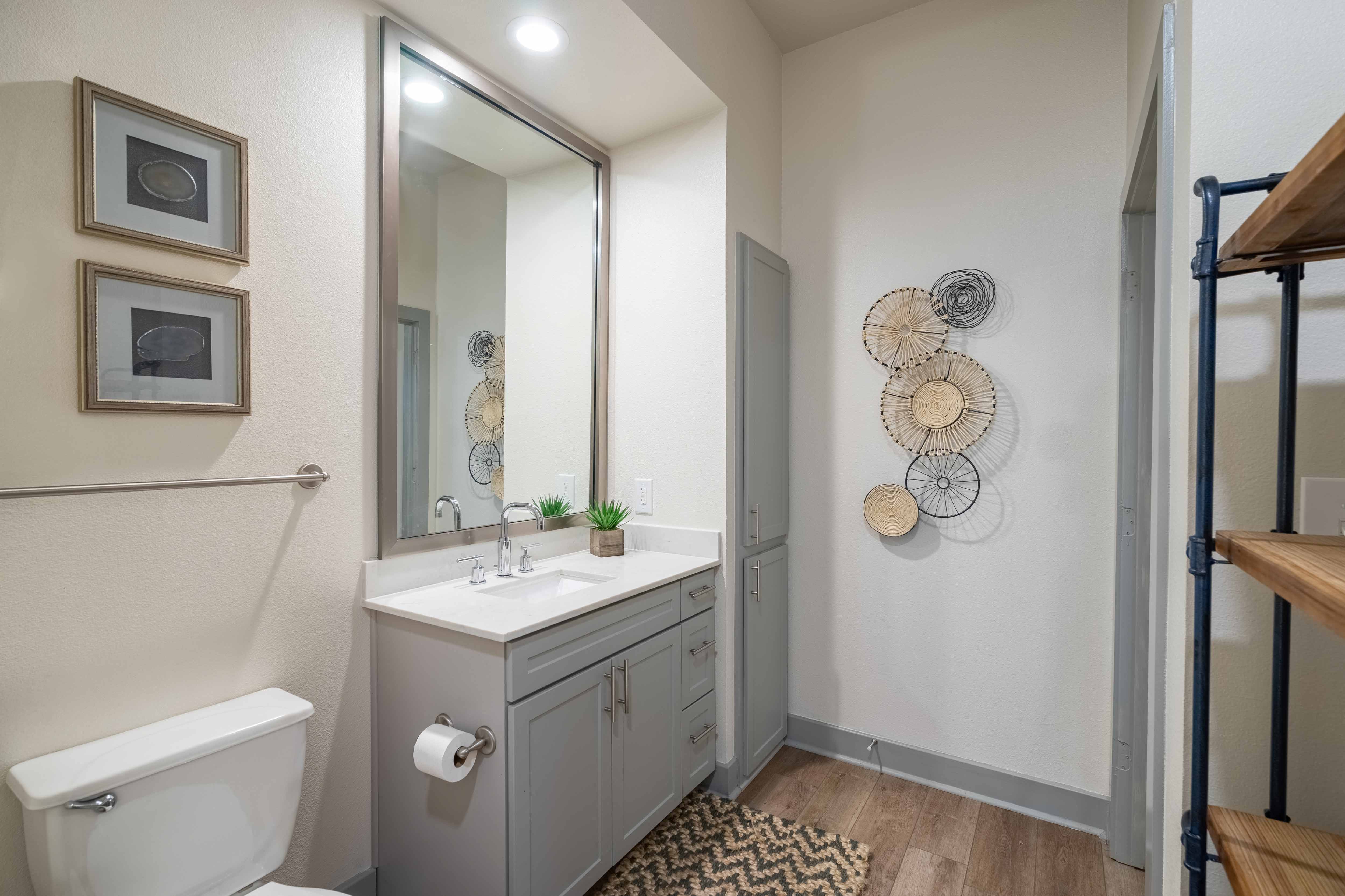 a bathroom with gray cabinets and a white toilet