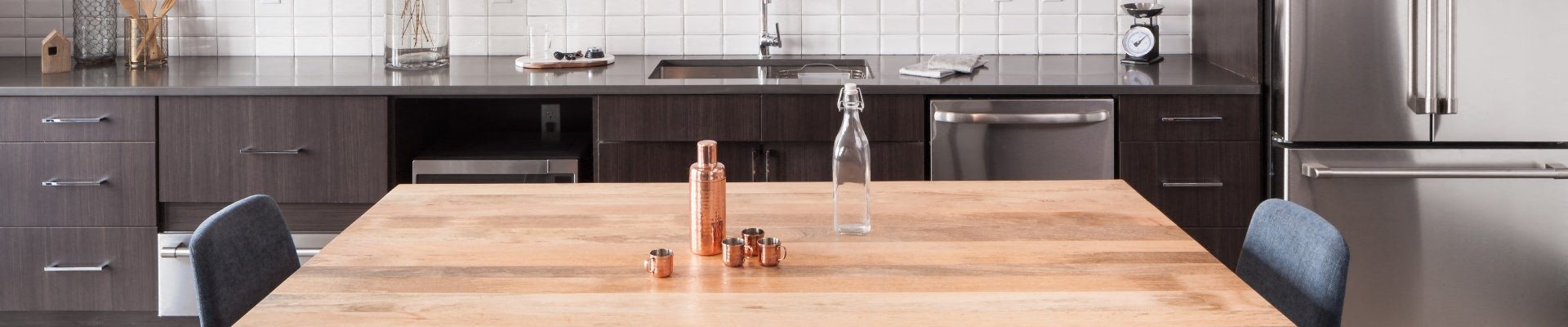 a kitchen with a wooden table and a stainless steel refrigerator